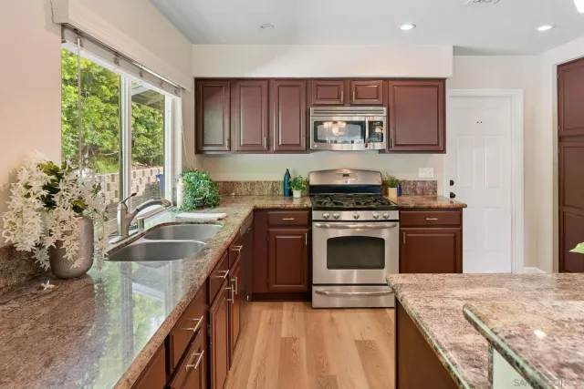a kitchen with granite countertop a stove sink and microwave