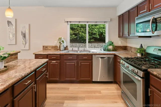 a kitchen with granite countertop stainless steel appliances a sink stove and cabinets