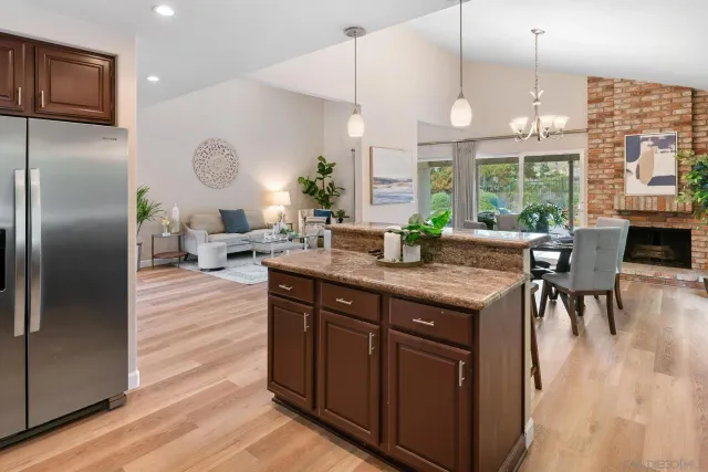 a kitchen with granite countertop a table chairs refrigerator and wooden floor