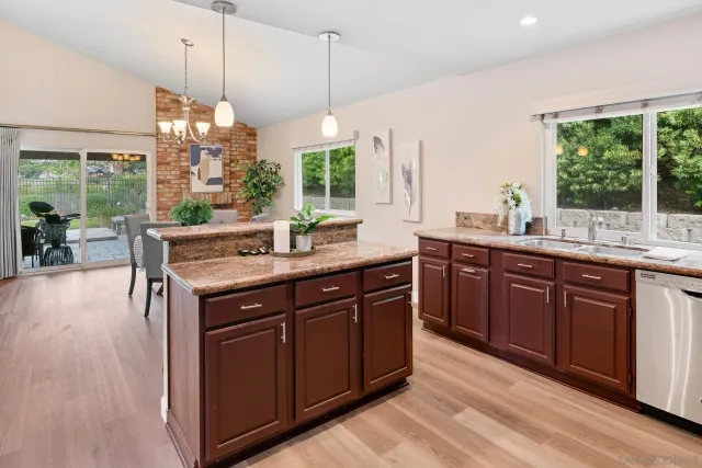 a kitchen with a sink a counter top space and living room view