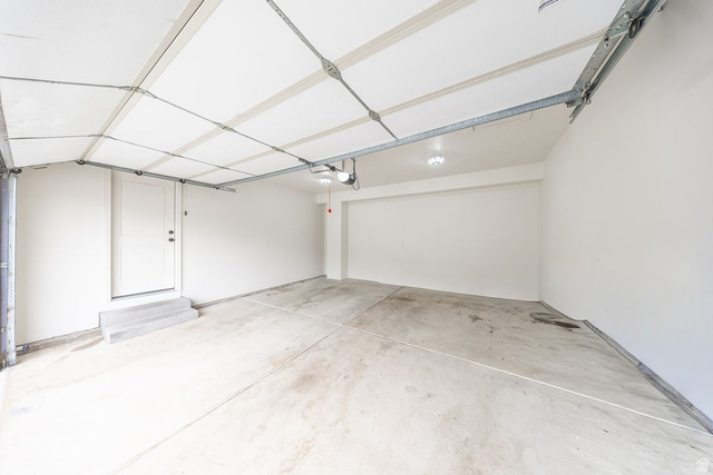 2169 Orchard Pines Loop East Bountiful, UT 84010 - Photo 28 of 32 Spacious garage featuring a concrete floor, painted white walls, and a finished ceiling with exposed garage door track system