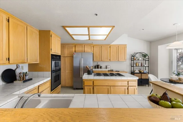 a kitchen with stainless steel appliances kitchen island granite countertop a sink and a refrigerator
