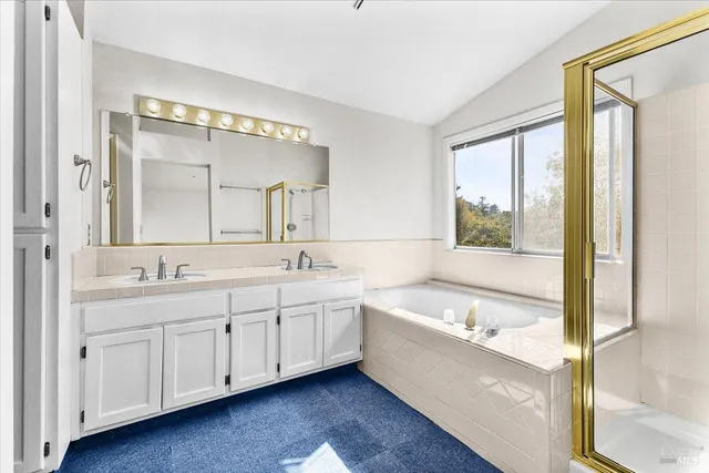 a bathroom with a double vanity sink and mirror with bathtub