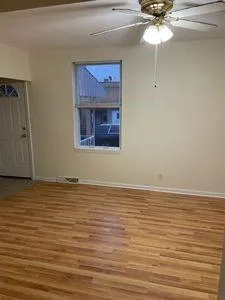 a view of empty room with wooden floor and fan