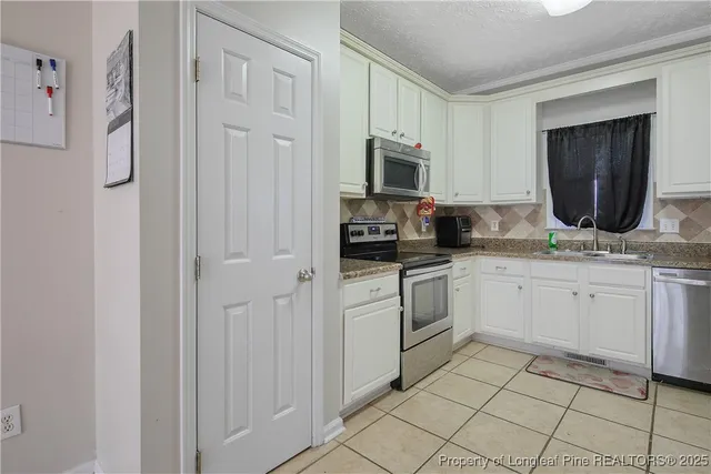 a kitchen with white cabinets a sink and white appliances