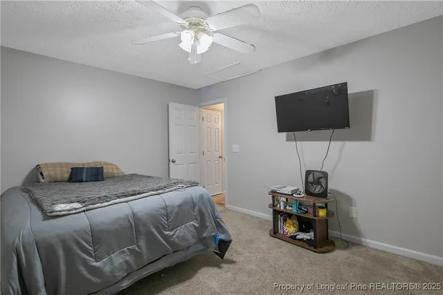 a bedroom with a bed a flat screen tv and a chandelier