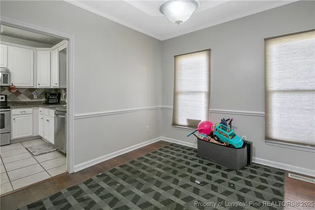 a room with a potted plant and open kitchen view