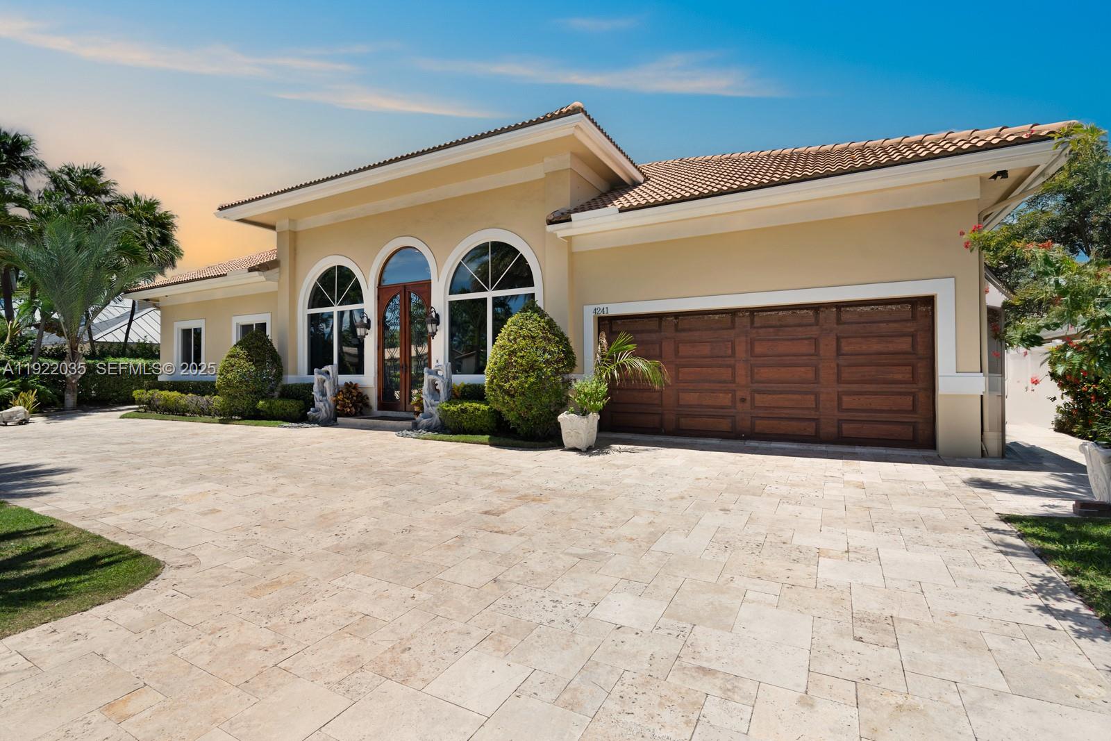 4241 Northeast 23rd Terrace Lighthouse Point, FL 33064 - Photo 2 of 26 a front view of a house with a yard and garage