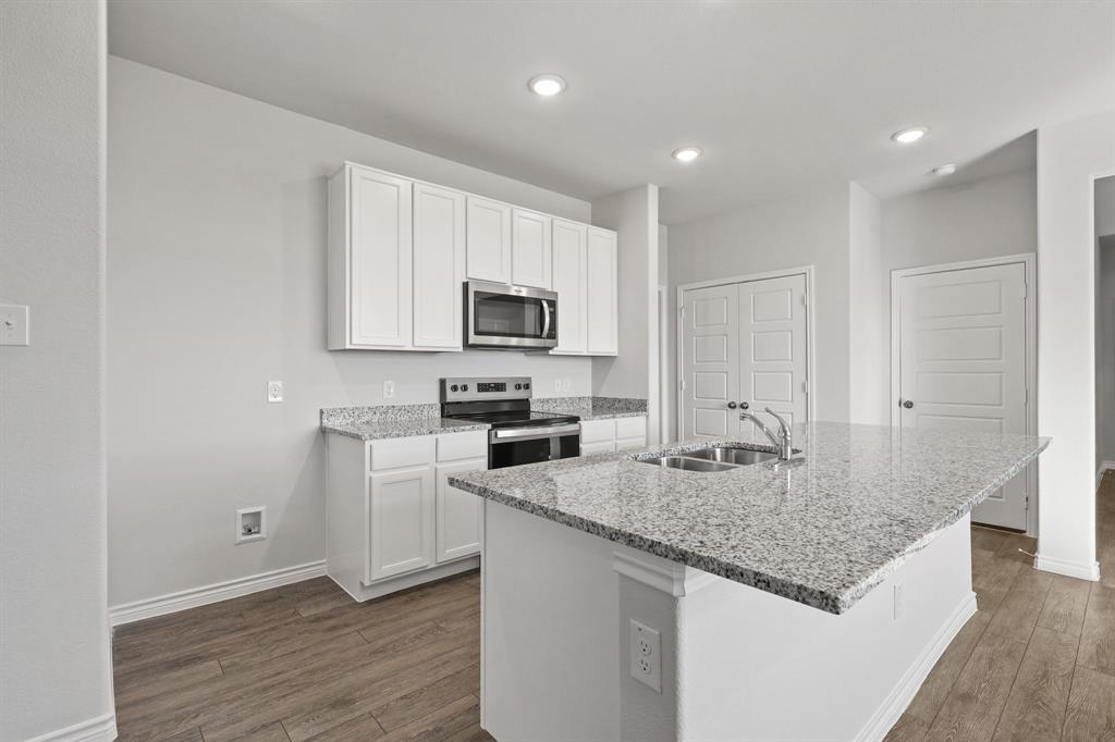 7904 Bald Cypress Road Fort Worth, TX 76123 - Photo 4 of 23 a kitchen with kitchen island granite countertop a stove sink and microwave