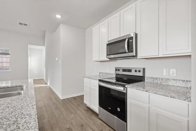 a kitchen with granite countertop wooden cabinets and stainless steel appliances