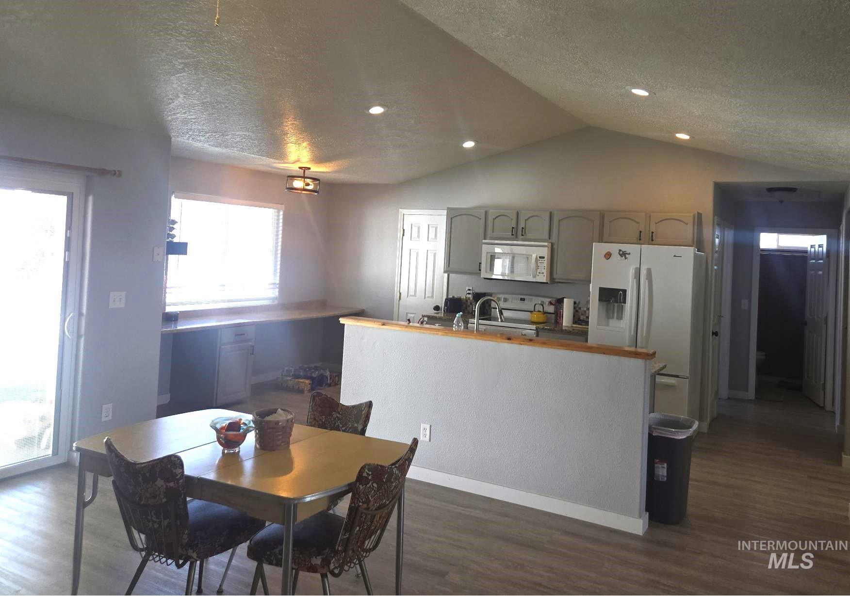 2480 West 9th Street Weiser, ID 83672 - Photo 6 of 17 Kitchen area featuring vaulted ceilings with recessed lighting, gray cabinetry with black hardware, and a built-in white microwave