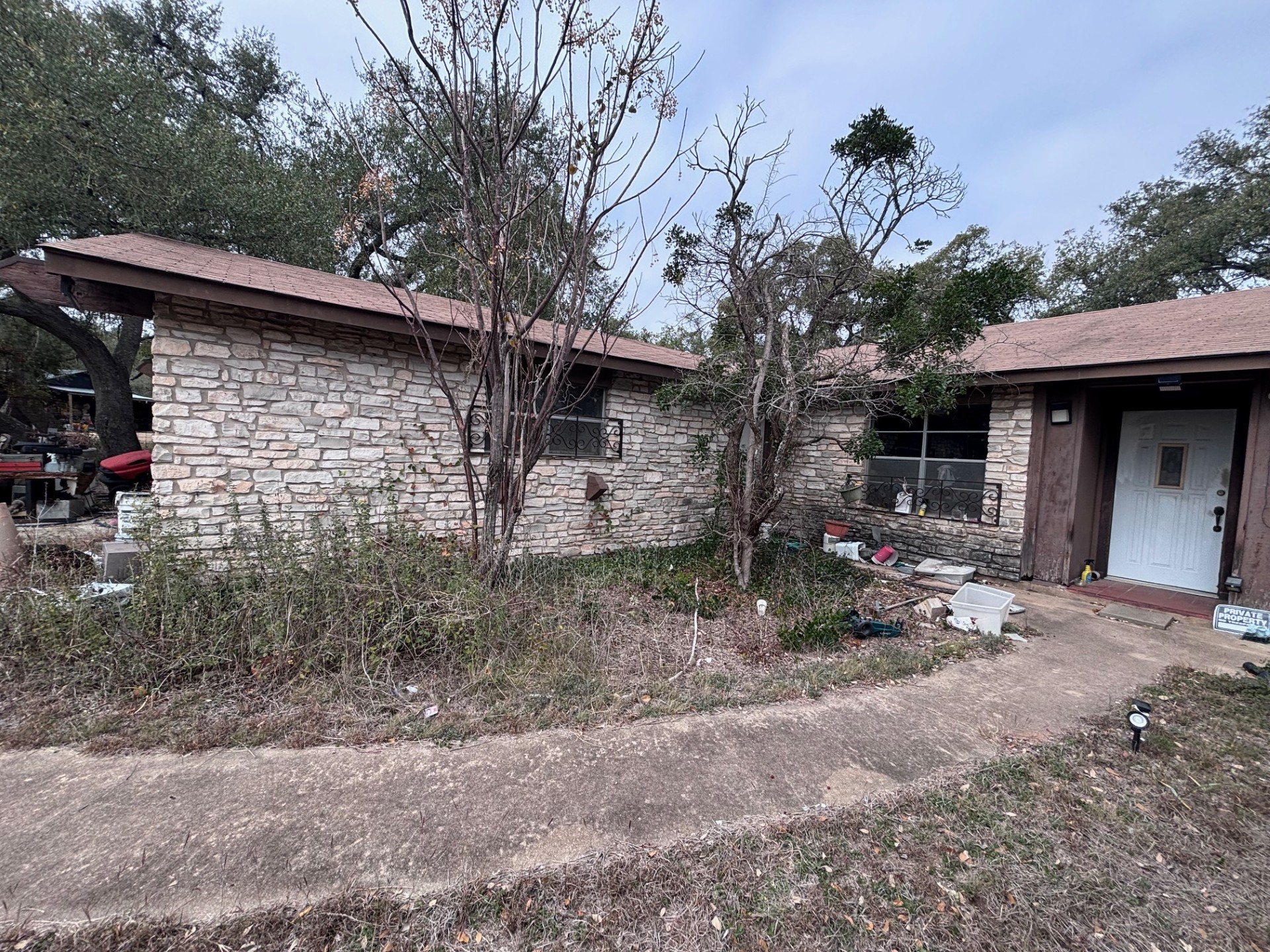 10302 Spring Circle Austin, TX 78736 - Photo 1 of 6 Single-story residence featuring a stacked stone façade, a gabled roofline with asphalt shingles, and a white entry door