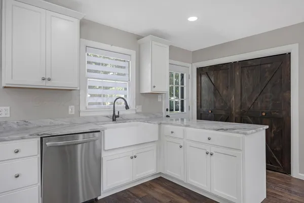 a kitchen with white cabinets sink and dishwasher with wooden floor