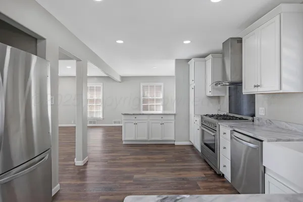 a kitchen with stainless steel appliances granite countertop a refrigerator and a stove top oven