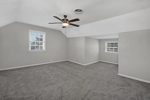 an empty room with windows and fan