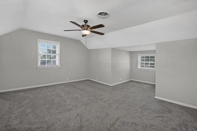 an empty room with windows and fan