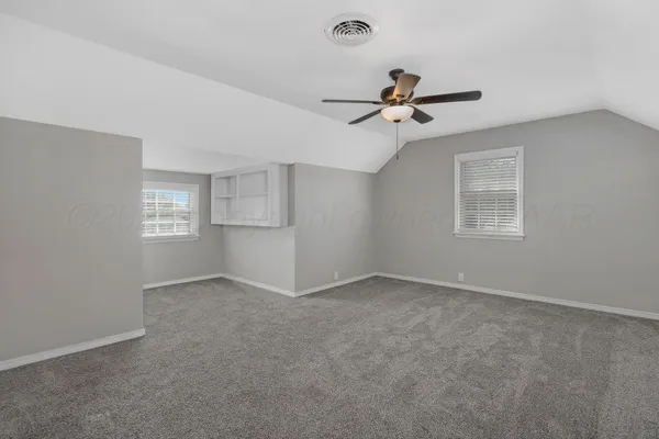 a view of an empty room with a ceiling fan and window
