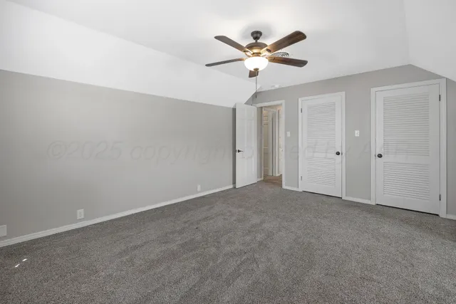 an empty room with a chandelier fan and windows