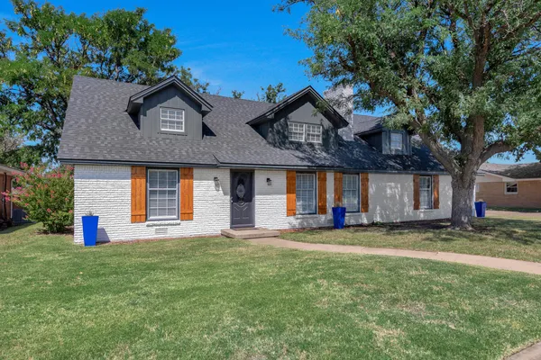 a view of a house with a yard and a large tree