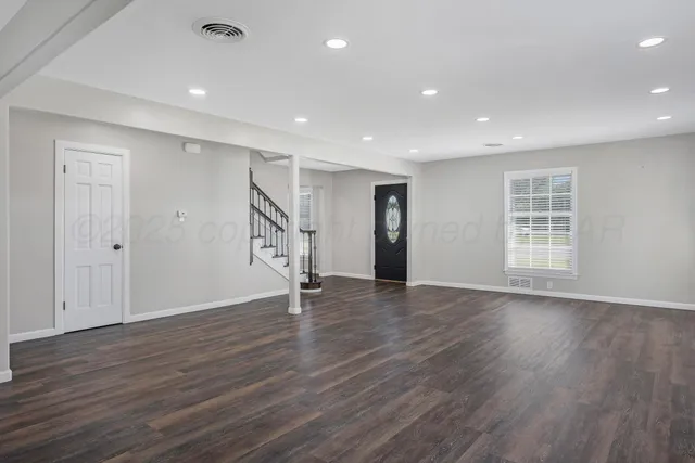 an empty room with wooden floor and window