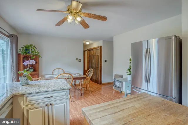 a open kitchen with stainless steel appliances granite countertop a stove top oven a sink a dining table and chairs with wooden floor