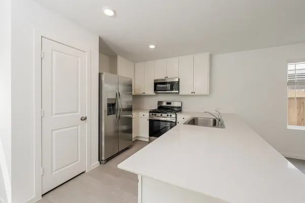 a kitchen with a refrigerator a sink and white cabinets
