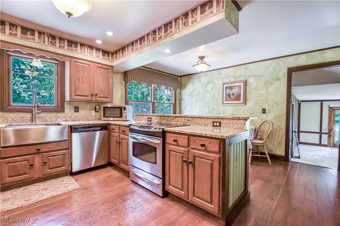 9715 Johnnycake Ridge Road Mentor, OH 44060 - Photo 25 of 50 Kitchen with stainless steel appliances, a peninsula, wood finished floors, and light stone countertops
