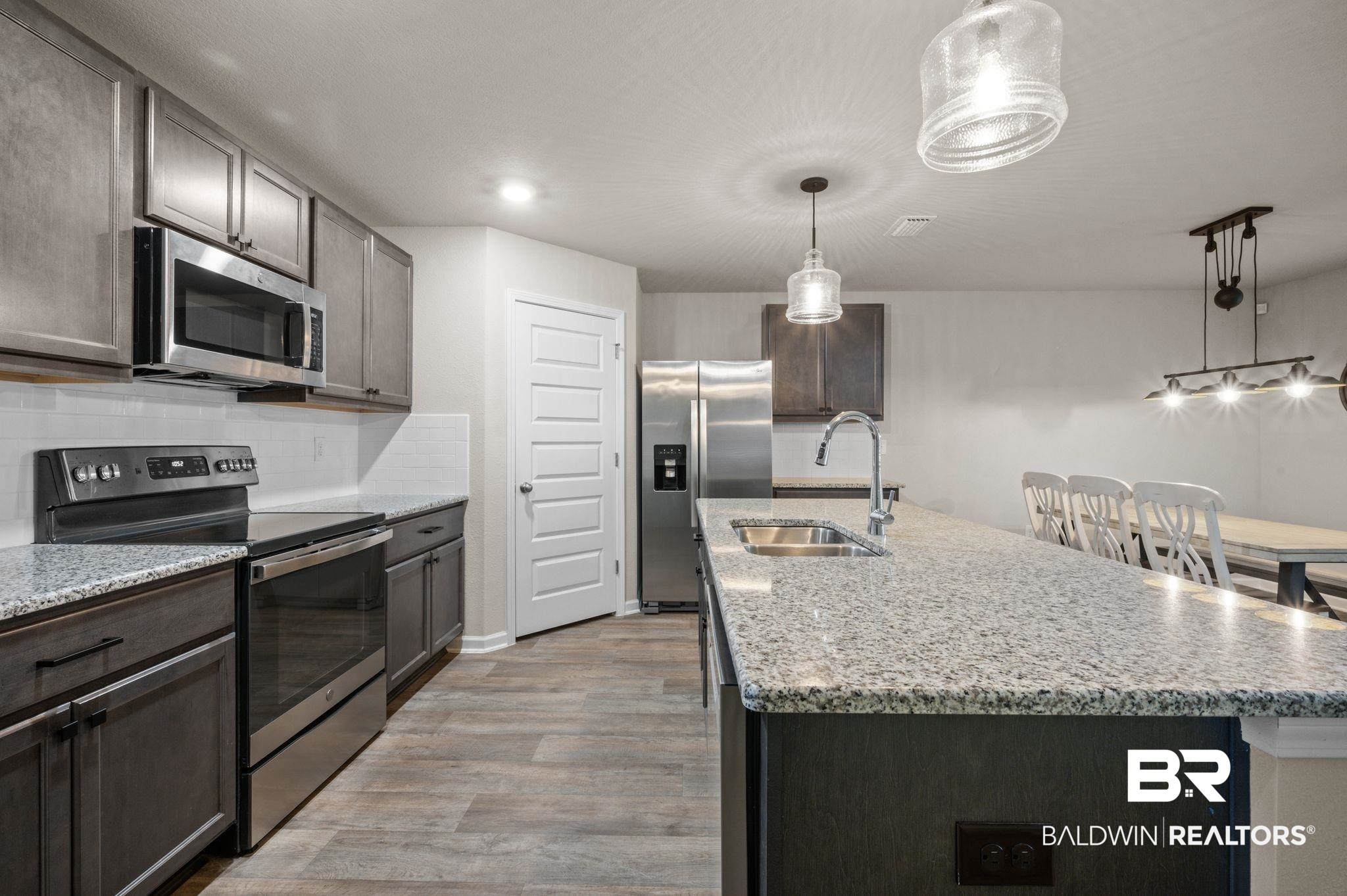10306 Brodick Loop Spanish Fort, AL 36527 - Photo 10 of 35 Kitchen featuring stainless steel appliances, light hardwood / wood-style floors, a center island with sink, and sink