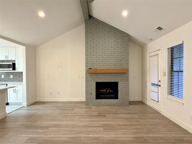a view of an empty room with a fireplace and a window