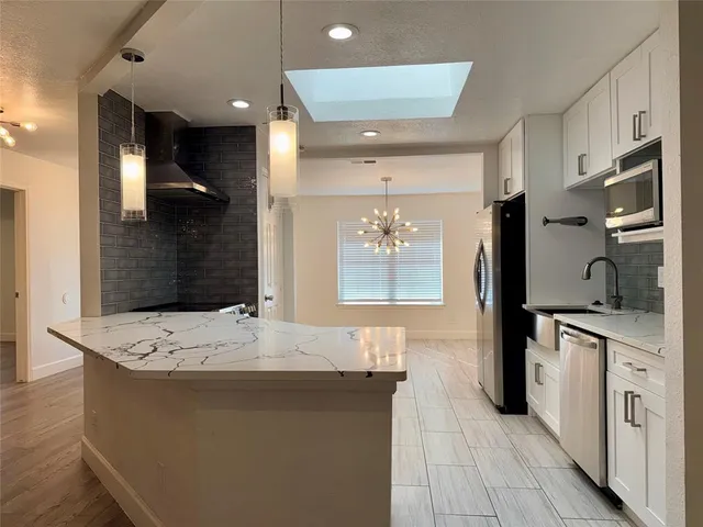 a large kitchen with stainless steel appliances a large counter top a stove a refrigerator and a sink