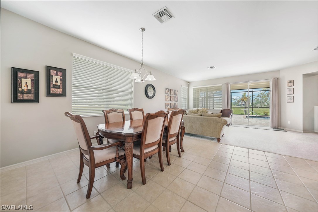 24501 Cabana Road Punta Gorda, FL 33955 - Photo 5 of 39 a view of a dining room and livingroom with furniture wooden floor a rug a flat screen tv a painting and a chandelier