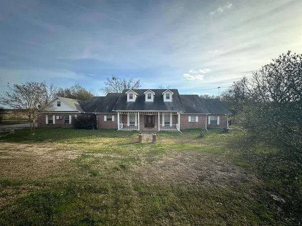 a view of a big house with a big yard and large trees