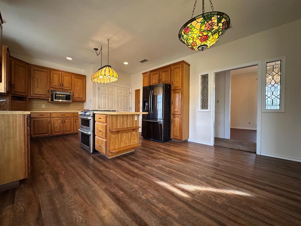 8099 Interstate 30 Frontage Road Cumby, TX 75433 - Photo 13 of 19 a kitchen with stainless steel appliances granite countertop a stove refrigerator and a microwave oven