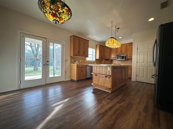 a kitchen with stainless steel appliances granite countertop a stove a refrigerator a microwave oven with a dining table and chairs