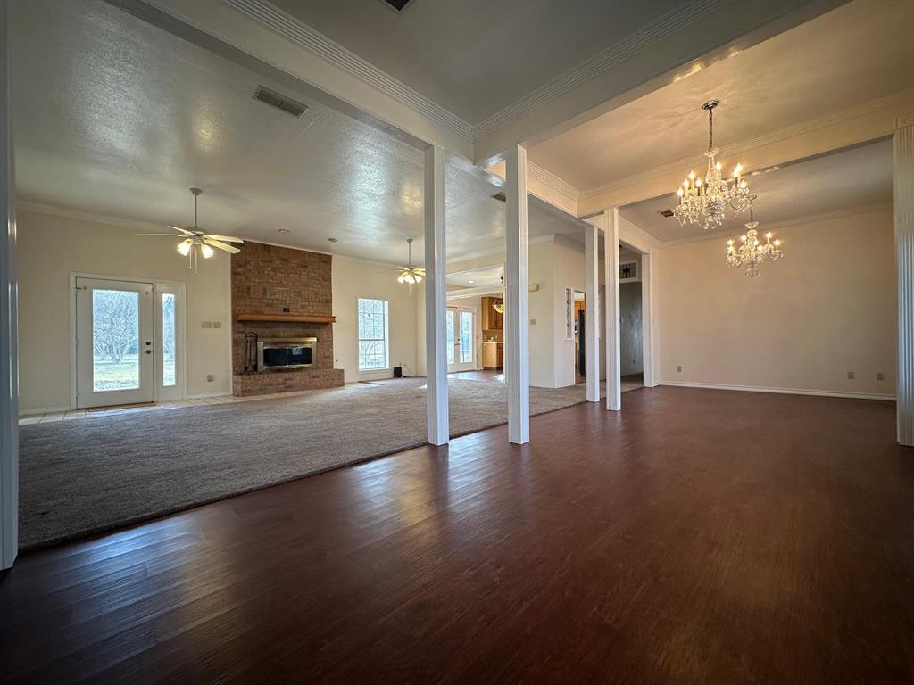 8099 Interstate 30 Frontage Road Cumby, TX 75433 - Photo 3 of 19 an empty room with a fireplace and chandelier