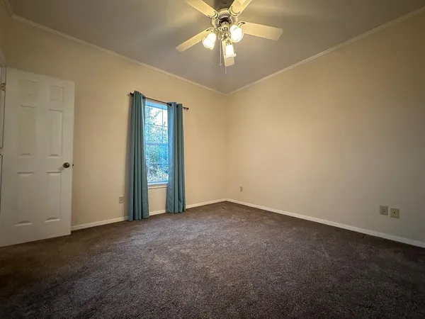 an empty room with a chandelier fan and windows