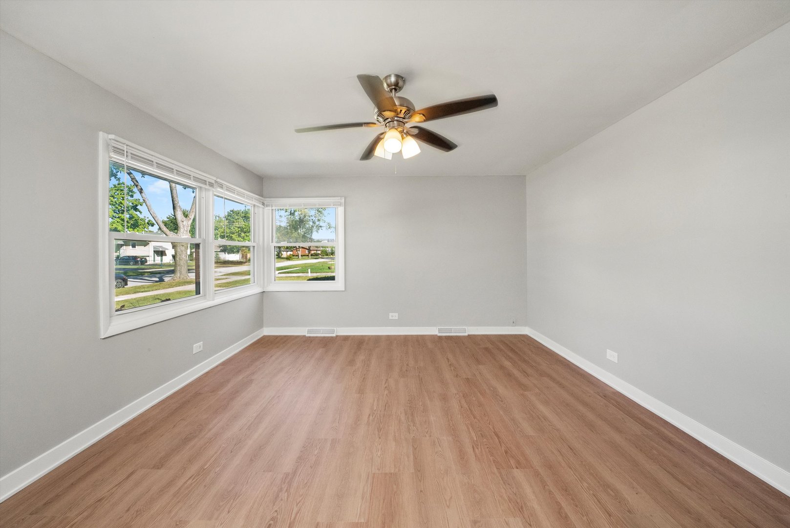 16333 Winchester Avenue Markham, IL 60428 - Photo 5 of 23 an empty room with wooden floor ceiling fan and windows