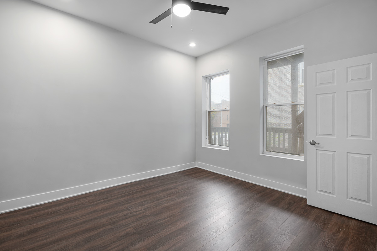 3003 West Fulton Street, Unit 1 Chicago, IL 60612 - Photo 11 of 29 an empty room with wooden floor chandelier fan and windows