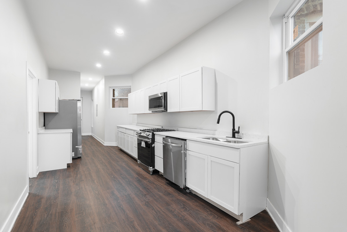 3003 West Fulton Street, Unit 1 Chicago, IL 60612 - Photo 7 of 29 a kitchen with stainless steel appliances granite countertop a stove top oven a sink and white cabinets with wooden floor
