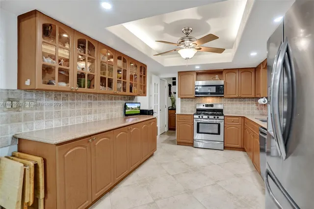 a kitchen with stainless steel appliances granite countertop a refrigerator a stove a sink and a microwave