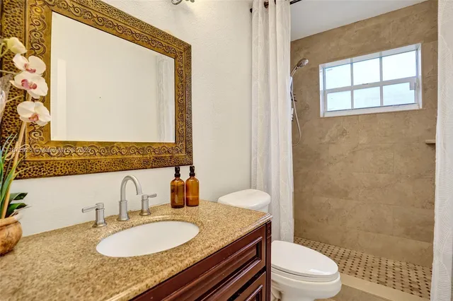 a bathroom with a granite countertop sink toilet a mirror and shower
