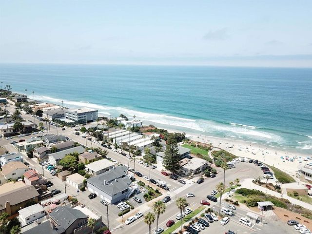 an aerial view of ocean and residential houses with outdoor space
