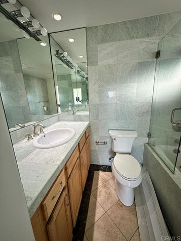 a bathroom with a granite countertop sink a toilet a mirror and shower