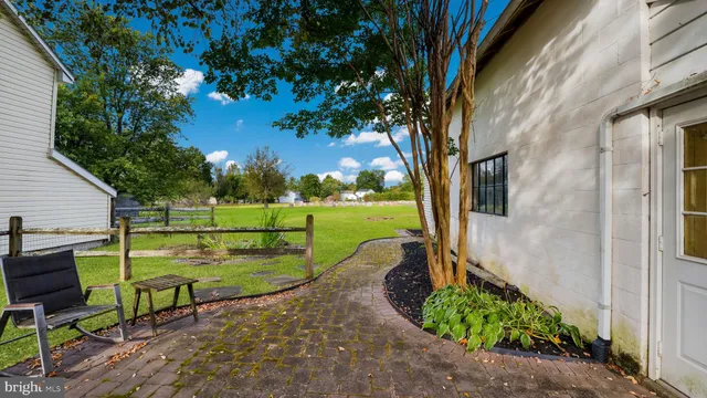 a view of a backyard with table and chairs potted plants and large tree