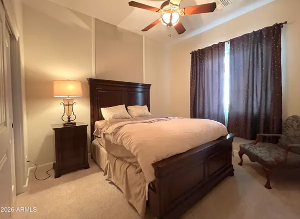 a bed sitting in a spacious bedroom next to a window and a chandelier