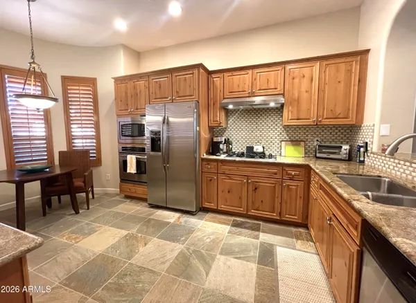a kitchen with granite countertop a refrigerator and wooden cabinets