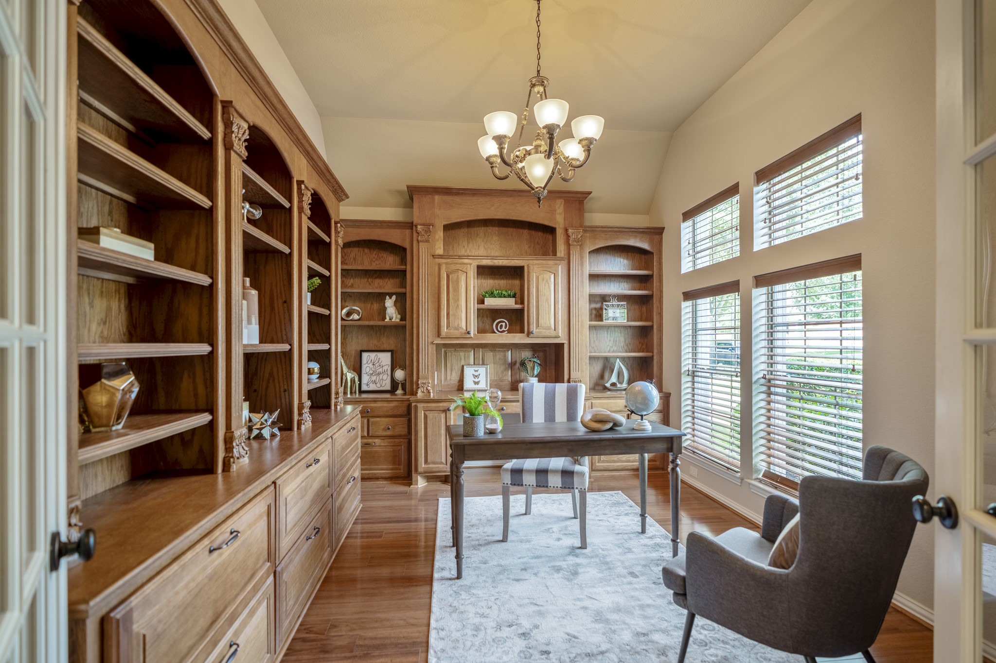 2407 Hendricks Lakes Drive Spring, TX 77388 - Photo 5 of 50 Working from home feels a little more inspired in this front study, where French doors, tall windows, and two walls of custom built-ins create a polished space just off the foyer. Rich wood cabinetry, detailed trim, file storage, display shelving, and lower cabinets give the room a library-like feel while keeping it practical for work, reading, or planning the day.