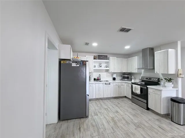a kitchen with refrigerator a stove top oven and white cabinets