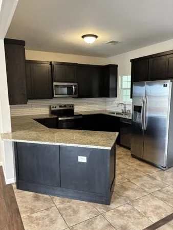 a kitchen with stainless steel appliances a sink a stove a microwave a counter top space and cabinets