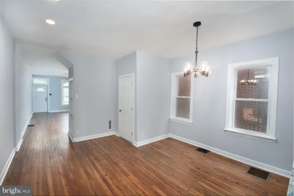 a view of empty room with wooden floor and windows